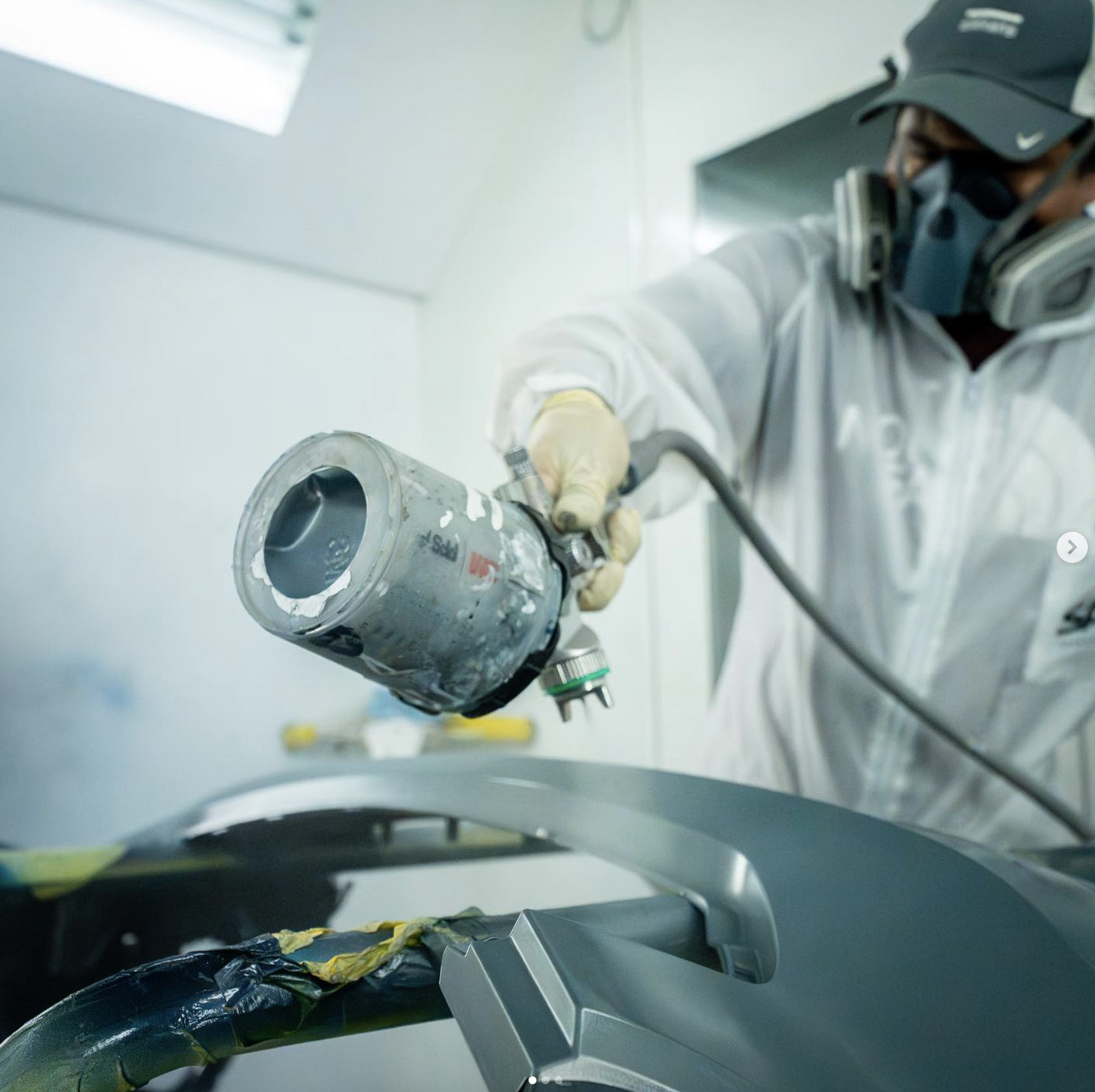 Collision repair technician preparing paint spray equipment